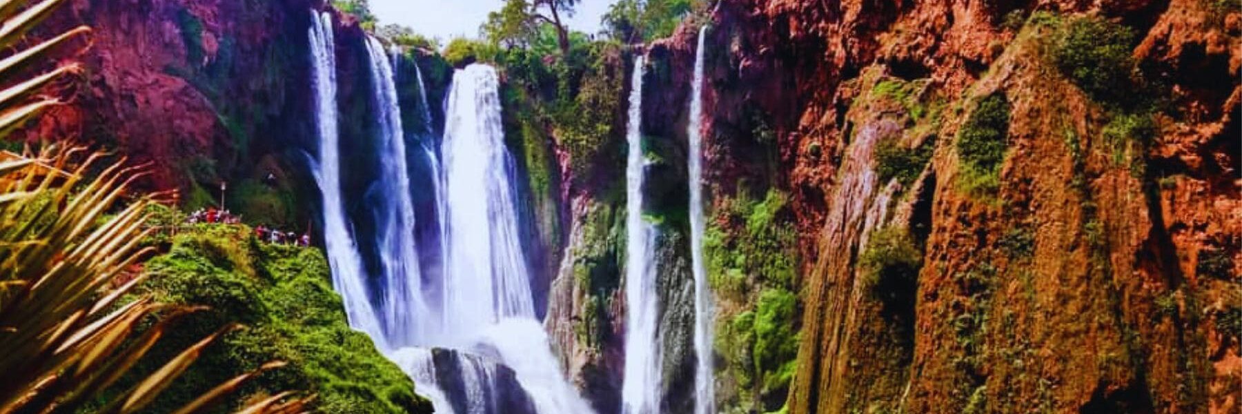 Majestic Ouzoud Waterfalls in Morocco surrounded by lush greenery, a perfect day trip from Marrakech.